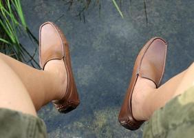 Man hanging leg over pond photo