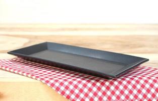 Black plate on checkered tablecloth on a table photo