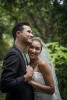 Bride and groom standing with green nature park background photo