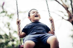 Adorable little boy having fun on a swing outdoors photo