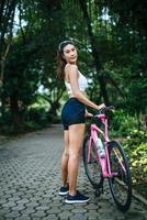 retrato de una mujer con una bicicleta rosa en el parque