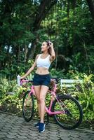 retrato de una mujer con una bicicleta rosa en el parque