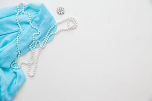 Top view of blue fabric and pearls and lipstick photo