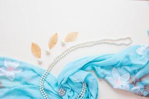 Top view of blue fabric and pearls and lipstick photo