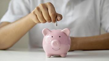 Women put silver coins into piglets to save money and save money for future investment. Financial concept photo