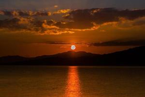 Orange sunset over mountains and water photo