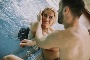 Pareja joven relajándose en la piscina de la piscina interior foto