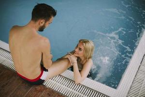 Young couple relaxing on the poolside of interior swimming pool photo