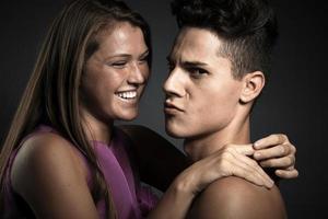 Retrato de una hermosa joven pareja feliz contra un fondo gris oscuro foto