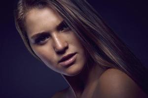 Beauty portrait of a young sexy woman against a dark blue background photo