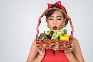 Mujer feliz sosteniendo una canasta de paja con fruta fresca foto