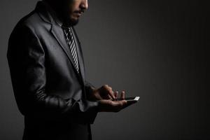 Businessman with his smartphone isolated on black photo
