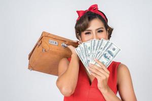 Retro fashionable woman holds luggage and money to travel photo