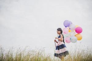 Little girl playing with balloons on meadows field photo