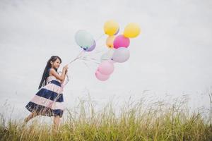 Little girl playing with balloons on meadows field photo