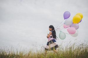 Little girl playing with balloons on meadows field photo