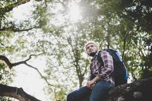 Young hipster man sitting on a tree branch in the park photo