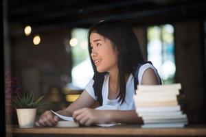 Young woman reading book sitting indoors in an urban cafe