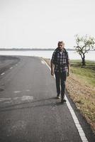 Hombre joven turista caminando por una carretera rural foto