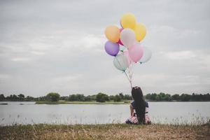 Little girl playing with balloons on meadow field photo