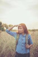 Vintage tone image of a beautiful young hipster woman with backpack in a meadow photo