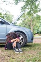 Mujer joven inconformista con un pinchazo en su coche foto