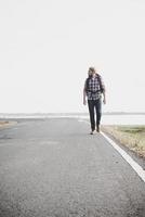 Hombre joven turista caminando por una carretera rural