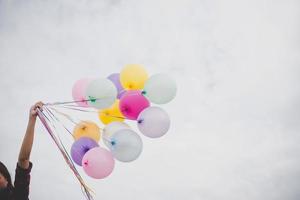 Woman with colorful balloons outside blue sky background photo