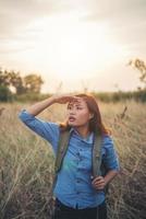 Vintage tone image of a beautiful young hipster woman with backpack in a meadow photo
