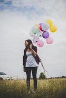 Beautiful young hipster woman holding colorful balloons outdoors photo