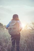 Vintage tone image of a beautiful young hipster woman with backpack in a meadow photo