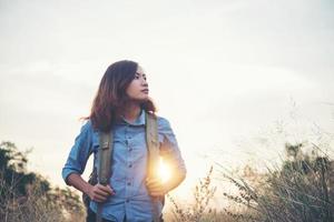 Vintage tone image of a beautiful young hipster woman with backpack in a meadow photo