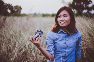 Happy young hipster woman with vintage camera in field photo