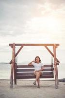 Bella mujer estirando en un columpio en la playa foto