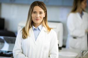 Investigadora en bata de laboratorio blanca de pie en el laboratorio biomédico foto