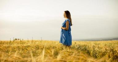 Young pregnant woman in blue dress relaxing outside in nature photo