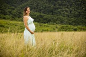 Young pregnant woman relaxing outside in nature photo