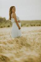 Joven embarazada en vestido blanco relajarse afuera en la naturaleza foto
