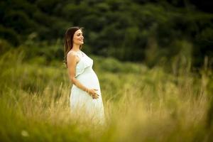 joven mujer embarazada relajarse afuera en la naturaleza foto