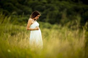 joven mujer embarazada relajarse afuera en la naturaleza