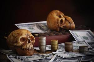 Two skulls with money on dark background photo