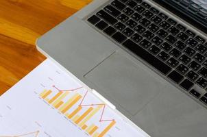 Workplace, analysis of graphics with a laptop on a wooden table photo