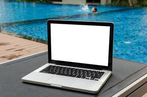 A laptop on a deckchair by a swimming pool photo