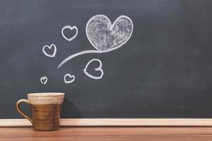 Coffee mug and heart doodle on the blackboard photo