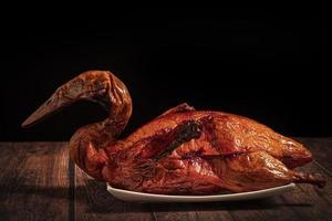 Whole roast duck on white plate on wooden table photo