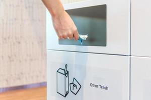 Young man putting plastic bag in recycling bin in the airport photo