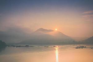 Sunrise over foggy mountains and water