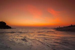 puesta de sol naranja sobre el agua en una playa foto