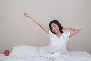 Mujer feliz que se extiende en la cama en casa por la mañana foto