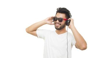 Hombre asiático sonriendo y riendo escuchar música con auriculares aislado sobre fondo blanco. foto